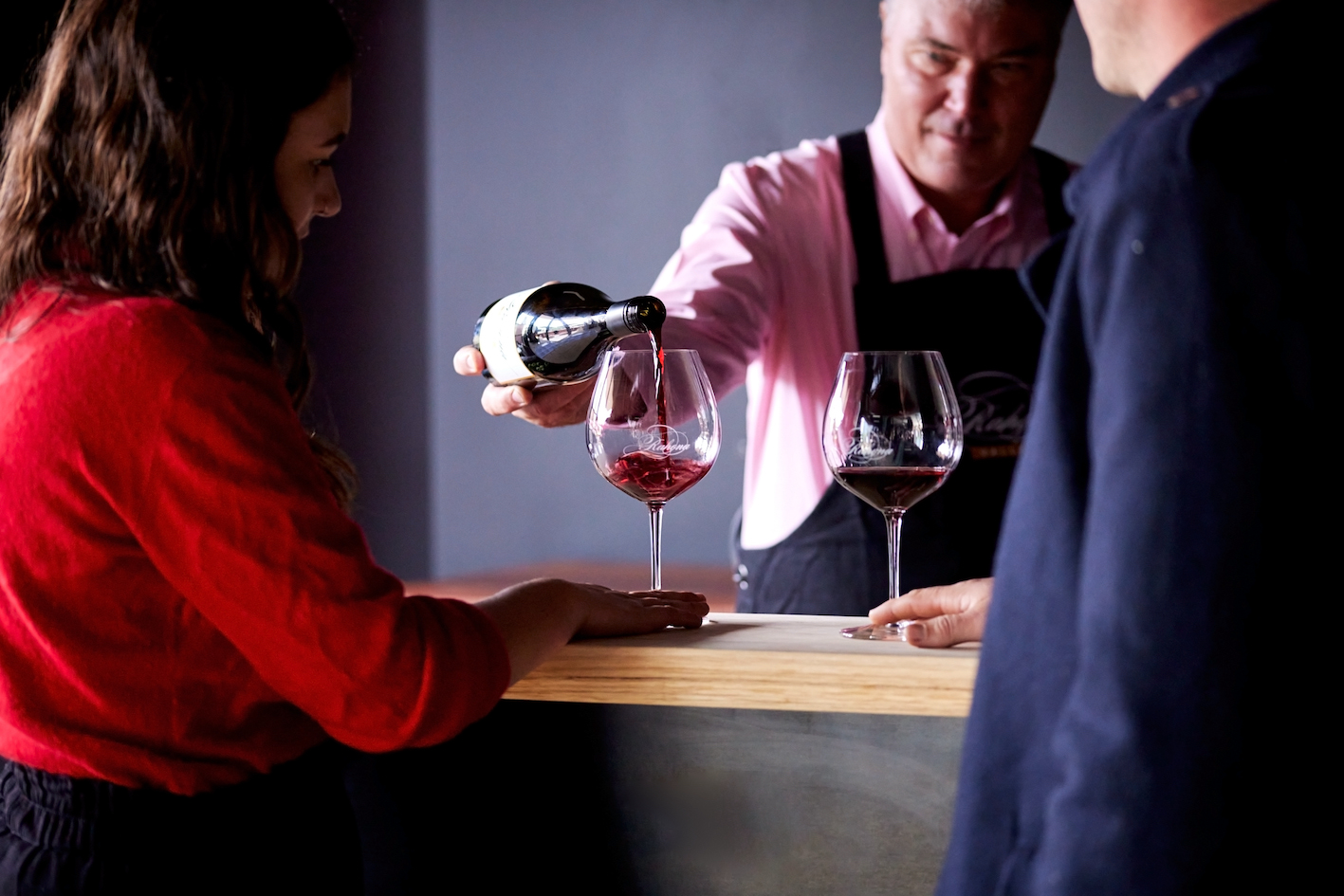 A man pouring wine for a couple